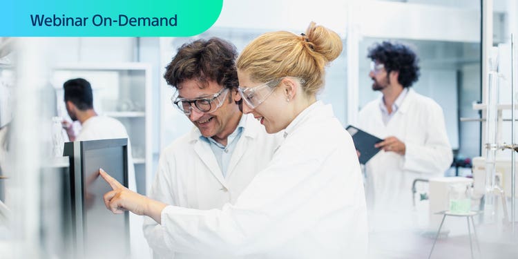 Webinar On-Demand. Two researchers in a bright lab environment happily looking at a computer display.
